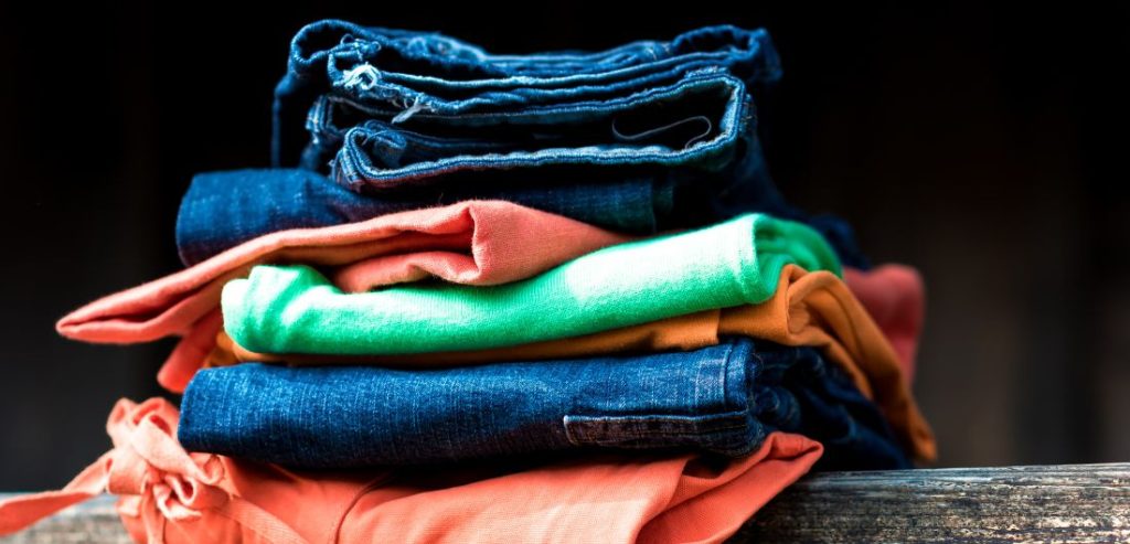 Kuva, jossa pinossa eri värisiä vaatteita.